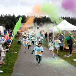 Keith Thorpe/Peninsula Daily News
Children run beneath a volley of tempra paint cannons at the start of Saturday's 1k Sun Fun Color Run at Carrie Blake Park, a featured event of the inaugural Sequim Sunshine Festival. The two-day fete, a celebration of Sequim's "sunny" reputation, featured a wide variety of events, displays, performances and activities.
