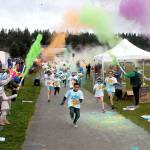 Children run beneath a volley of tempera paint cannons at the start of the 1K Sun Fun Color Run at Carrie Blake Park in 2020. (Keith Thorpe/Peninsula Daily News)