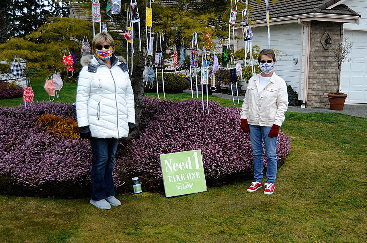 In Sunland North, Danette Bemis, left, and Kathy Tiedeman continue to hang cloth masks they make for free in Bemis front yard. Donations are accepted to help continue the effort, the friends said. (Matthew Nash/Olympic Peninsula News Group)