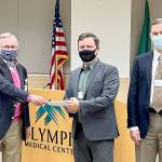 Bruce Skinner, Olympic Medical Center Foundation executive director, left, presents a check for $55,000 at last weeks OMC Commissioners meeting to Chair John Nutter, center, and OMC CEO Darryl Wolfe. (Submitted photo)