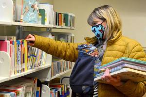 Anne Koomen and baby Jasper, 6 weeks, browse the Port Townsend Library childrens section for books Jaspers two older siblings might like. Libraries across the North Olympic Peninsula are now open for short in-person visits and self-checkout of books, CDs and DVDs. The Port Townsend Librarys grab-and-go hours are from 2 p.m. to 5 p.m. Tuesdays and Thursdays and from 10 a.m. to 1 p.m. Saturdays. (Diane Urbani de la Paz/Peninsula Daily News)