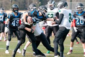 East Jefferson’s Bjorn Danaan-Devas hangs onto the ball while being tackled by a Klahowya Eagle during a Saturday afternoon home game in Chimacum.