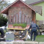 Port Angeles police investigators examine evidence at the scene of a garage fire in the 100 block of East Fifth Street that authorities suspect was caused by arson. (Keith Thorpe/Peninsula Daily News)