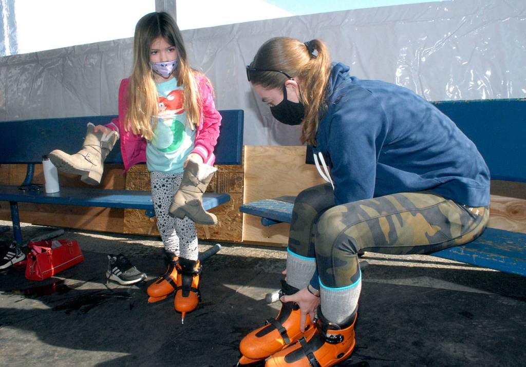 Stephanie Dickinson of Sequim and her dauughter, Raelynn Dickinson, 4, prepare to take to the ice on Saturday at the Port Angeles Winter Ice Village. (Keith Thorpe/Peninsula Daily News)