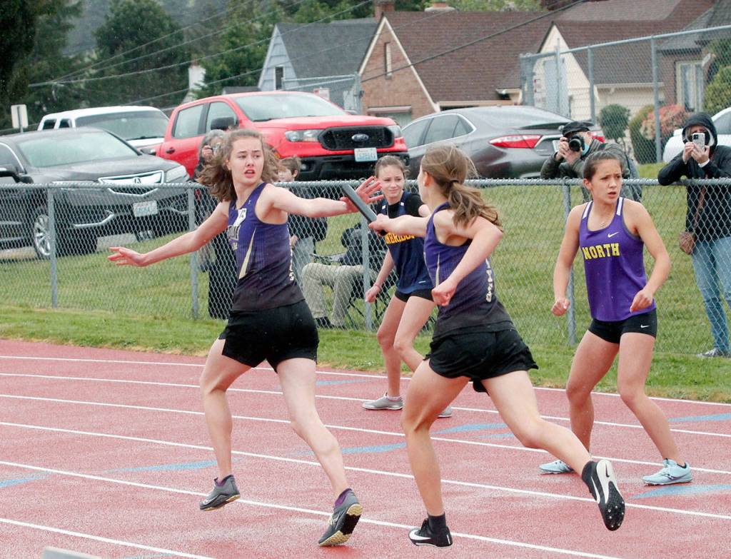 Anastasia Updike takes the baton from Taryn Johnson during Sequims first-place 4x400 relay run. (Mark Krulish/Kitsap News Group)