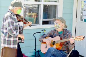 Fiddler Alea Waters, left, and guitarist Lang Russel provide free music outside Port Townsends Recovery Cafe last week. (Diane Urbani de la Paz/Peninsula Daily News)
