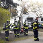 Clallam County District 2 firefighters work at the scene of a blaze that damaged a travel trailer at 2442 E. Highway 101, Space 25, of the Monroe Estates RV park in Port Angeles on Wednesday. District 2 Fire Chief Jake Patterson said his department was summoned after a passerby knocked on the door of a nearby trailer and informed that resident that the trailer was on fire, then left the scene. No one was at home when firefighters arrived, and no one was injured. Patterson said the cause of the blaze was unknown. Law enforcement authorities are investigating the blaze as possible arson. (Keith Thorpe/Peninsula Daily News)