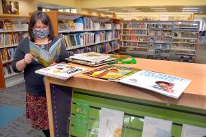 Jennifer Knight, youth services librarian at the Port Angeles Library, looks over a selection of books featured in Dolly Partons Imagination Library. (Keith Thorpe/Peninsula Daily News)