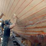 Shipwright Pete Steion of Port Townsend sands the bottom of the cutter Tally Ho on Tuesday. (Keith Thorpe/Peninsula Daily News)