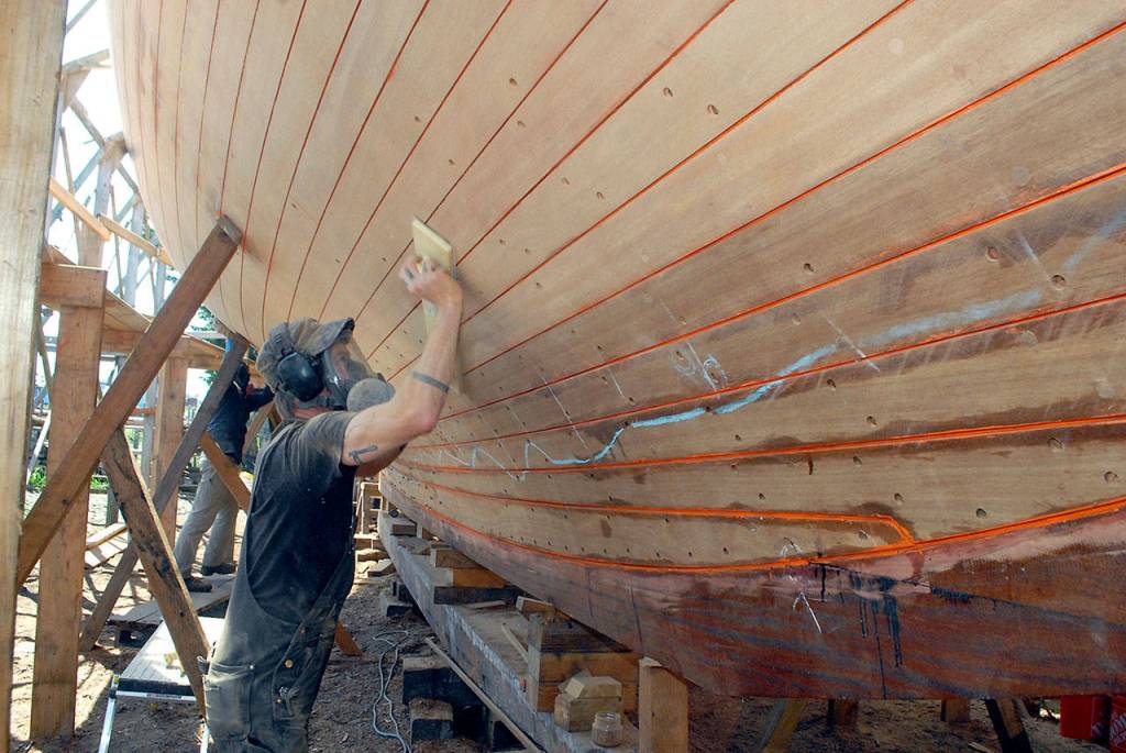 Shipwright Pete Steion of Port Townsend sands the bottom of the cutter Tally Ho on Tuesday. (Keith Thorpe/Peninsula Daily News)
