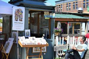 Artist Mike Biskup takes in the sun on Water Street in Port Townsend, where he sells his art from a vintage elevator cage. Diane Urbani de la Paz/Peninsula Daily News