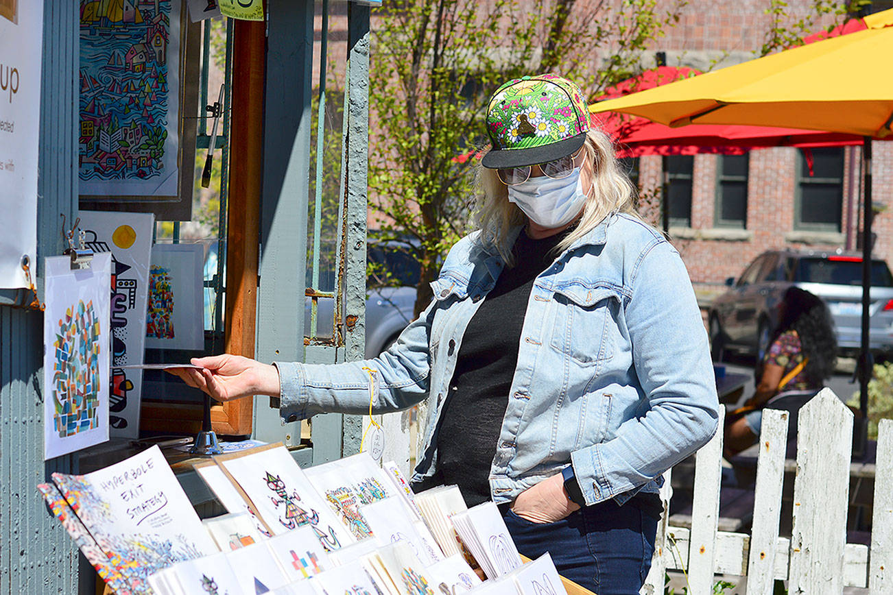 Bonnie Romani of Ocean Shores admires Mike Biskup's outdoor art gallery in downtown Port Townsend. Biskup and his work appear each weekend at the foot of Water Street. Diane Urbani de la Paz/Peninsula Daily News