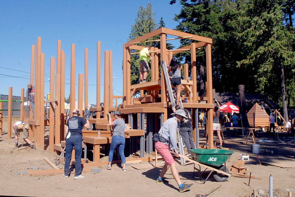 Volunteers work to construct a play structure at the Generation II Dream Playground at Erickson Playfield in Port Angeles on Saturday. (Keith Thorpe/Peninsula Daily News)