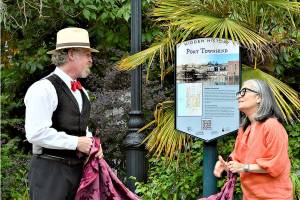 Historian Nathan Barnett of Olympic Peninsula Steam and Port Townsend Mayor Michelle Sandoval unveil a guide to the new Hidden History signs Thursday afternoon at Washington and Taylor streets. Fourteen interpretive signs, each revealing a facet of the citys past, are being posted around Uptown and downtown Port Townsend. (Diane Urbani de la Paz/Peninsula Daily News)