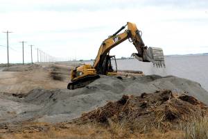 An excavator moves dirt and sand on Ediz Hook on Friday at the former site of the Olympic Peninsula Rowing Associations boat house at the edge of Port Angeles Harbor. (Keith Thorpe/Peninsula Daily News)