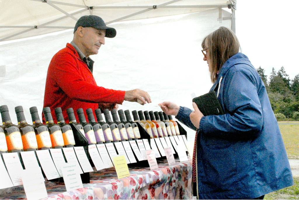 John Hershfield of Maple Valley-based Gustoblene presents a sample of lavender-flavored balsamic vinegar to Patty Reid of Bremerton at Washington Lavender east of Port Angeles. (Keith Thorpe/Peninsula Daily News)