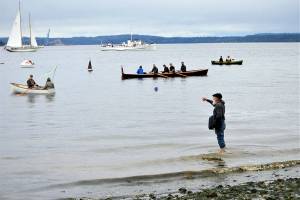 Len Feldman sends flowers to Port Townsend Bay in honor of Brion Toss, the famed rigger, teacher and author who died in June 2020. The smallest boat on the water, a one-fifth scale model of a 1933 Sam Crocker-designed catboat named Katy, was launched during the procession Wednesday morning; it bears Toss ashes. (Diane Urbani de la Paz/Peninsula Daily News)