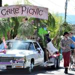 Among the entrants coming back to the Rhody Festival Grand Parade is the Cake Picnic Cadillac, pictured in the 2019 parade through Uptown Port Townsend. Flanking the float are bicyclist Tao Johnston, pedestrian Ryan Charrier and Meredith Milholland with daughter Gitte, then 1, in her stroller. (Diane Urbani de la Paz/Peninsula Daily News)