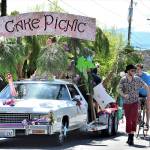 Among the entrants coming back to the Rhody Festival Grand Parade is the Cake Picnic Cadillac, pictured in the 2019 parade through Uptown Port Townsend. Flanking the float are bicyclist Tao Johnston, pedestrian Ryan Charrier and Meredith Milholland with daughter Gitte, then 1, in her stroller. (Diane Urbani de la Paz/Peninsula Daily News)