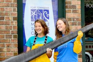 Holding a piece of baleen from a bowhead whale, Port Townsend Marine Science Center exhibit and outreach specialist Mandi Johnson, left, and aquarium specialist Marley Loomis stand before the centers newly acquired Flagship Landing building in downtown Port Townsend. (Diane Urbani de la Paz/Peninsula Daily News)