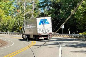 A semi-truck got caught in downed power lines along U.S. Highway 101 at milepost 302 that are believed to have been pulled down by an overheight vehicle Wednesday afternoon.  (Photo Courtesy of Brinnon Fire Department)