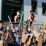 Teaching artists Margie McDonald, at left on the porch, and Michele Soderstrom led a four-afternoon course on building superhero armor for youngsters at the Northwind Art school at Fort Worden State Park in July. Their graduates are Callum Johnson, 14, Kaladry Groenig, Satria McKnight and Owen Griffith, all 11, Reid Armstrong, 10, Caleb Armstrong, 9, Byron Eisele, 8, and Nigel Groenig, 13. (Diane Urbani de la Paz/Peninsula Daily News)