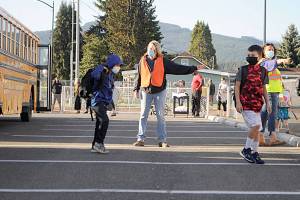 Bus driver Veronica Brenner, center, and paraeducator Liz Joers direct students to classrooms at Helen Haller Elementary and buses to Greywolf Elementary on Wednesday morning for the first day of school. (Matthew Nash/Olympic Peninsula News Group)