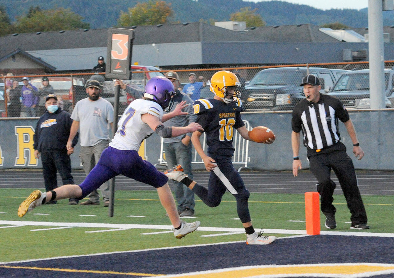Lonnie Archibald/for Peninsula Daily News Forks quarterback Logan Olson outruns Sequims Mason King for a touchdown in the second quarter of the Spartans 56-28 season-opening win over the Wolves.