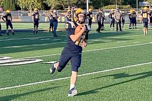 Forks' Kaleb Blanton runs with the ball during pregame warmups before the Spartans' home opener with Sequim last Friday. Blanton and Forks debuted new home uniforms with gold and white shoulder stripes and gold numbers in the game. (Michael Carman/Peninsula Daily News)