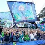 FILE - In this July 25, 2021, file photo, members of the Emerald City Supporters and other fans wave flags and cheer before an MLS soccer match between the Seattle Sounders and Sporting Kansas City in Seattle. Fans attending most pro sporting events in Seattle will soon be required to show proof they've been vaccinated against COVID-19 or that they've tested negative for the virus. The NFL's Seahawks, MLS's Sounders, NHL's Kraken and the University of Washington all announced updated policies Tuesday, Sept. 7, 2021, for fans attending games this season.  (AP Photo/Ted S. Warren, File)