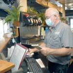 Rick Mathis, owner of Smugglers Landing Restaurant & Lounge in Port Angeles, tallies a customers bill on Tuesday. (Keith Thorpe/Peninsula Daily News)