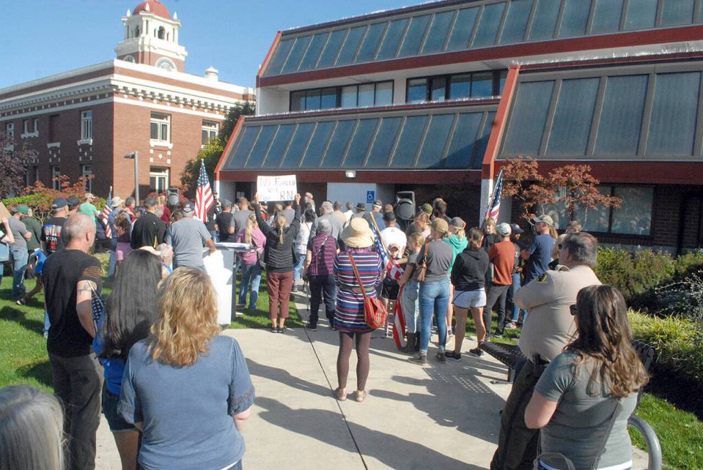 People gather in front of the Clallam County commissioners meeting room on Tuesday to listen to public comment on a mandate requiring businesses to check proof of vaccination for the coronavirus before admitting customers inside for indoor dining or drinking. (Keith Thorpe/Peninsula Daily News)