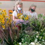 Sisters Jenny Edwards, left, and Julia Ahrndt, both of Port Angeles, assemble flower bouquets that will be distributed to teachers and staff members of the Port Angeles School District at an assembly session with volunteers on Thursday at Hamilton School. The pair collected more than 4,000 flowers from their own flower farms, along with donations from other farms and area gardeners, that will be arranged in tin can vases and given out in the days to come to about 450 school district employees as a token of thanks for their hard work in tending to the needs of children. (Keith Thorpe/Peninsula Daily News)