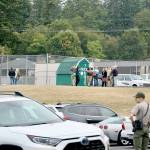 Port Angeles High School faculty and staff wait by the tennis courts on campus for further instructions after students were evacuated from the building on Tuesday. (Ken Park/Peninsula Daily News)