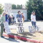 About 10 anti-vaccination protestors gather outside the Port Townsend High School campus Wednesday afternoon, holding a variety of signs such as "the vaccine is slow euthanasia" and equating getting the COVID-19 vaccine to playing a game of Russian roulette. (Zach Jablonski/Peninsula Daily News)