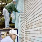 Paul Stutseman, on scaffolding, and Ardith Hansel, foreground, paint a house as part of a church project. (Dave Logan/For Peninsula Daily News)