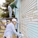 Paul Stutseman, on scaffolding, and Ardith Hansel, foreground, paint a house as part of a church project. (Dave Logan/For Peninsula Daily News)