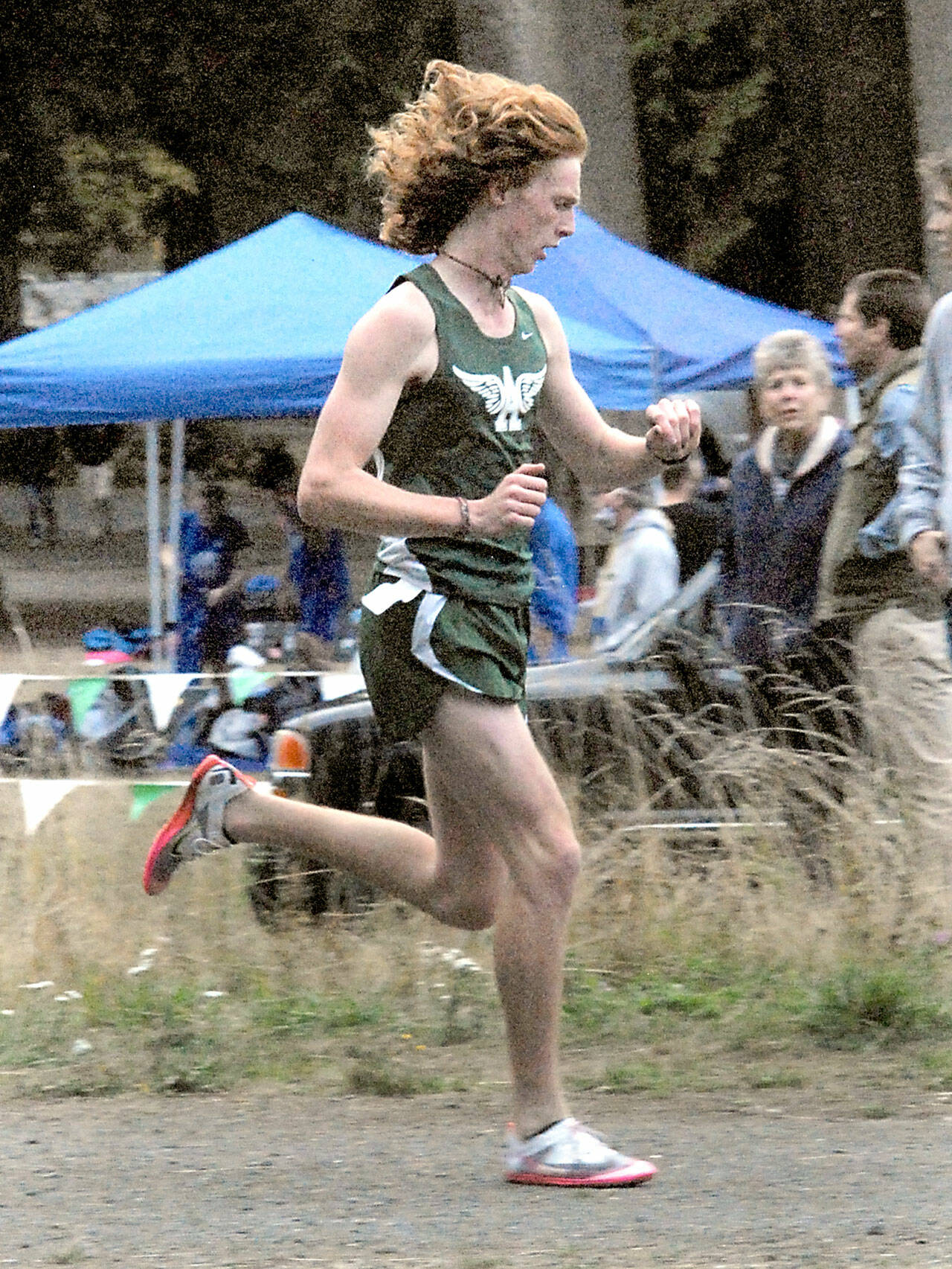 Jack Gladfelter of Port Angeles checks his watch for an intermediate time before going on to win the varsity boys cross-country race at Lincoln Park in Port Angeles on Wednesday. (Keith Thorpe/Peninsula Daily News)