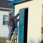 Volunteer Sandy Tweed, a fine artist in Port Townsend, finishes painting a door to the Pats Place bathroom unit on Friday. (Diane Urbani de la Paz/Peninsula Daily News)