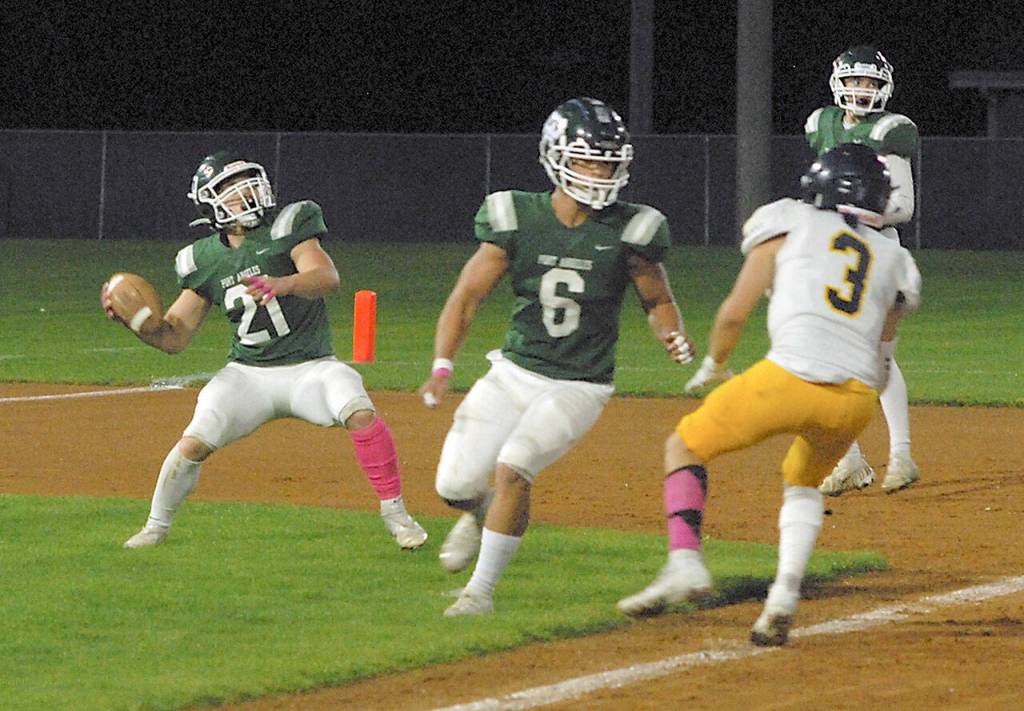 Keith Thorpe/Peninsula Daily News Port Angeles Daniel Cable, left, slips back to pass after receiving a lateral pass from quarterback Parker Nickerson, far right, as teammate Jaziel Livingston sets up to block Bainbridges Jeff Utter on Friday in Port Angeles.