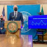 Gov. Jay Inslee, front, talks to reporters in Olympia earlier this month as Secretary of Health Umair Shah looks on. Inslee announced Thursday that 94 percent of state workers complied with a state mandate to either get the COVID-19 vaccine or be approved for an exemption. (Rachel La Corte/The Associated Press)