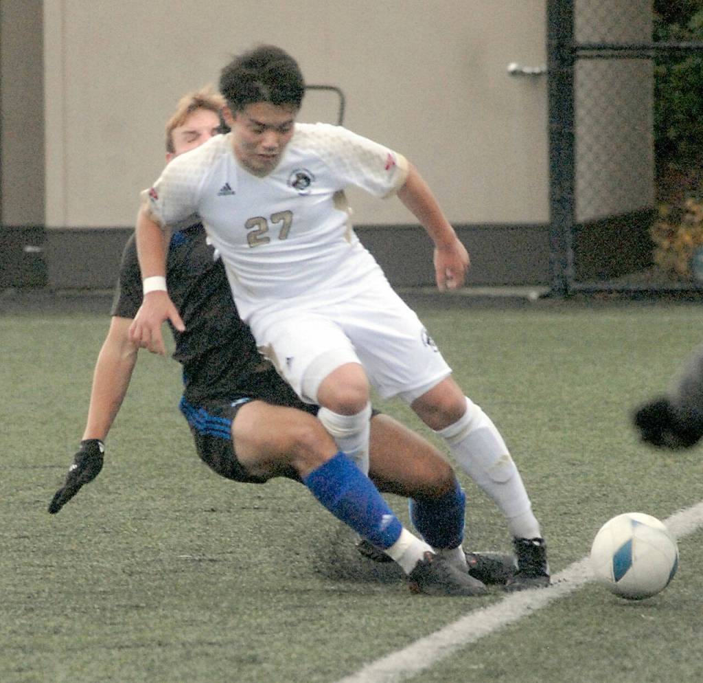 Peninsulas Yusaku Shimakura, front, tries to fend off a tackle by Rogues Jonny McCoy during Saturdays NWAC quarterfinal match in Port Angeles. (Keith Thorpe/Peninsula Daily News)