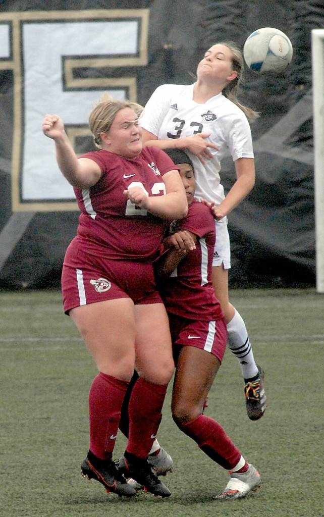 Peninsulas Cerese McMillian, top, takes the header over the top of Pierces Emily Bryant, left, and JKira Wolbrecht during Saturdays playioff match at Wally Sigmar Field in Port Angeles. (Keith Thorpe/Peninsula Daily News)