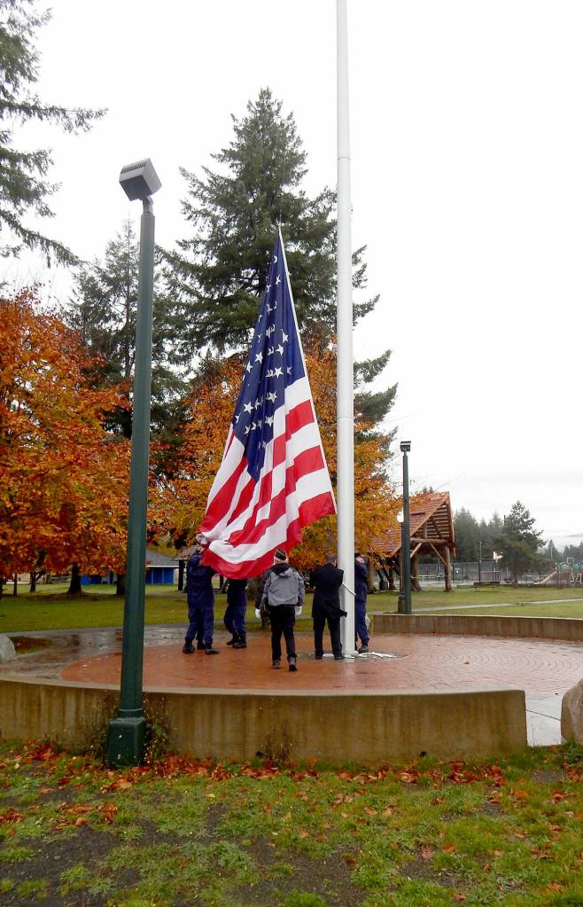 U.S. Coast Guard Station Quillayute River members assist Forks Mayor Tim Fletcher with raising the U.S. flag on Thursday at Tillicum Park as American Legion Post 106 Commander Gale Bolin looks on. Christi Baron/Olympic Peninsula News Group