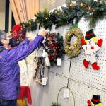 Marla Tolliver of Neah Bay examines wreaths and hanging holiday decorations on Saturday at the annual Christmas Cottage craft fair at Vern Burton Community Center in Port Angeles. The free event, which continues Sunday from 10 a.m. to 4 p.m., features a wide variety of holiday crafts created by a collection of local artists and artisans. (Keith Thorpe/Peninsula Daily News)