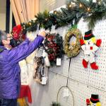 Marla Tolliver of Neah Bay examines wreaths and hanging holiday decorations on Saturday at the annual Christmas Cottage craft fair at Vern Burton Community Center in Port Angeles. The free event, which continues Sunday from 10 a.m. to 4 p.m., features a wide variety of holiday crafts created by a collection of local artists and artisans. (Keith Thorpe/Peninsula Daily News)