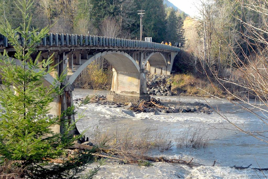 Keith Thorpe/Peninsula Daily News
WSDOT workers stand on the closed U.S. 101 bridge as a swollen Elwha River flows beneath on Tuesday west of Port Angeles.