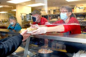 Ruth Cadden of Port Angeles, right, hands out a turkey assembled by meal helpers Linda Crabb, left, and Doug Crabb, both of Sequim, during Wednesdays annual Thanksgiving Eve community feast at the Salvation Army Community Center in Port Angeles. (Keith Thorpe/Peninsula Daily News)