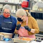 Volunteers Anita Schmucker and Judy Robinett are among the veteran crew members who served hundreds of takeout Thanksgiving meals at the Tri-Area Community Center on Thursday. (Diane Urbani de la Paz/Peninsula Daily News)