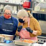 Volunteers Anita Schmucker and Judy Robinett are among the veteran crew members who served hundreds of takeout Thanksgiving meals at the Tri-Area Community Center on Thursday. (Diane Urbani de la Paz/Peninsula Daily News)